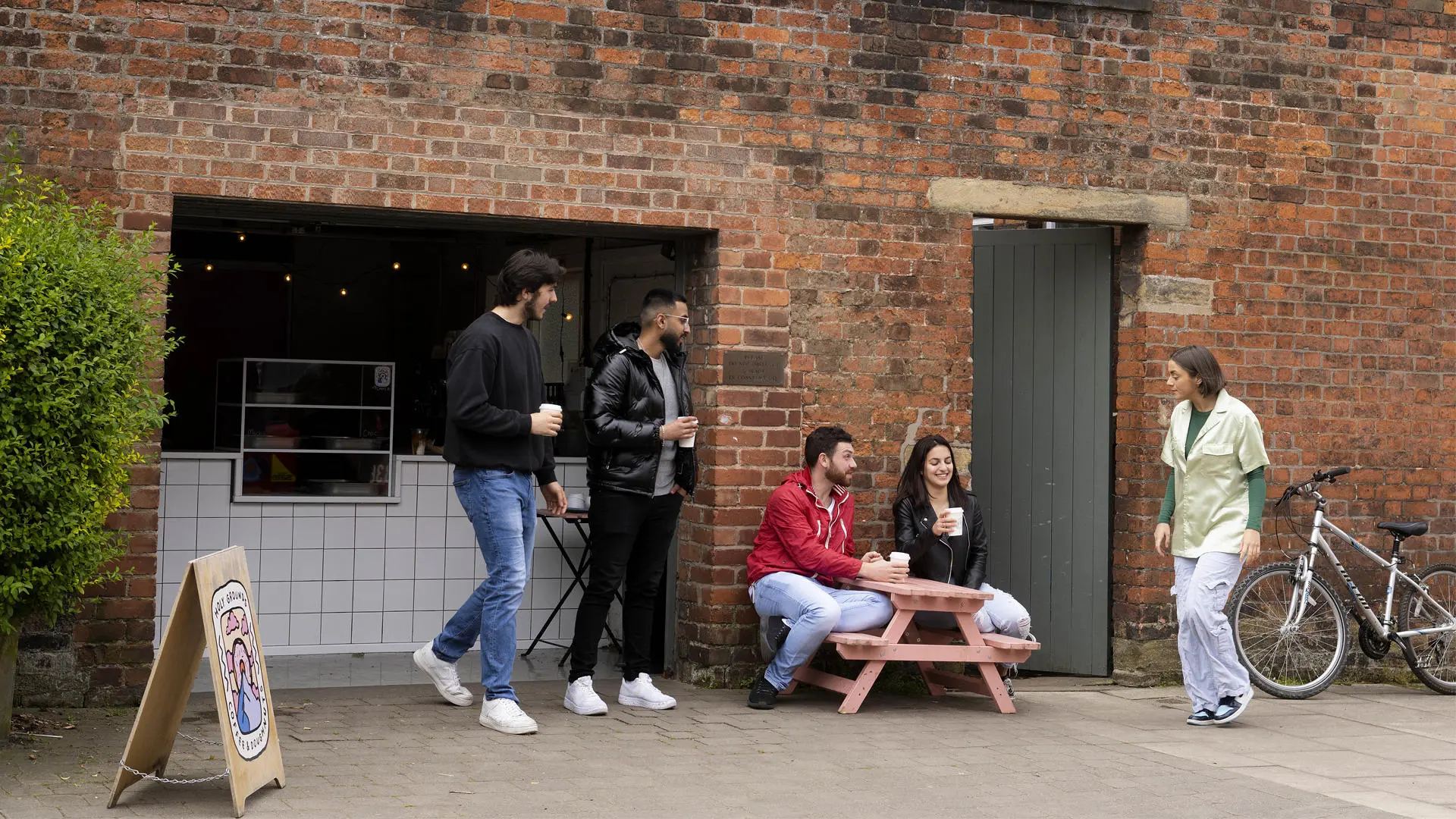 students sat outside holy grounds at outdoor tables