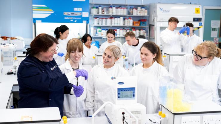 Students and lecturer in a laboratory wearing white coats