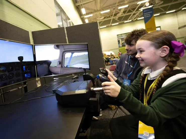 Primary school student flies an aeroplane simulator.