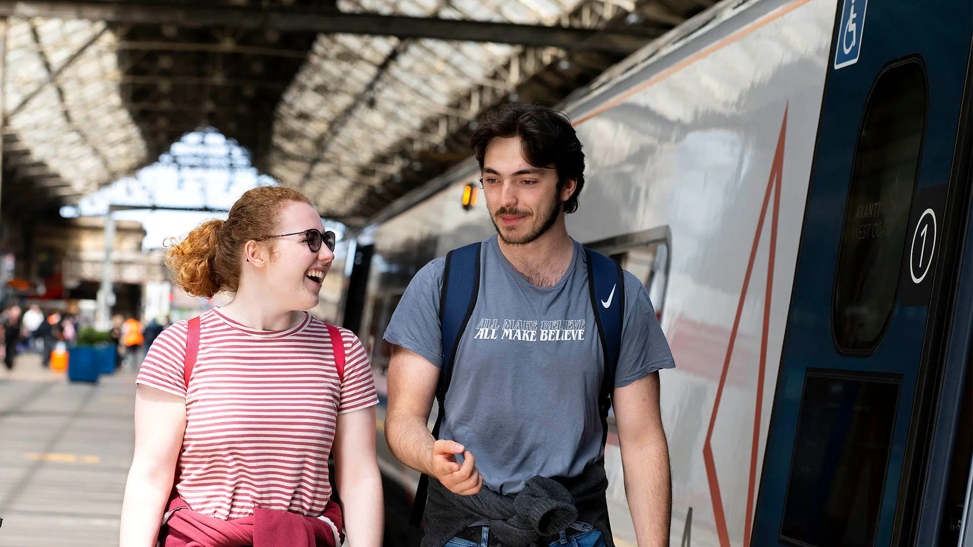 Two students walking and talking at Preston train station about to board a train