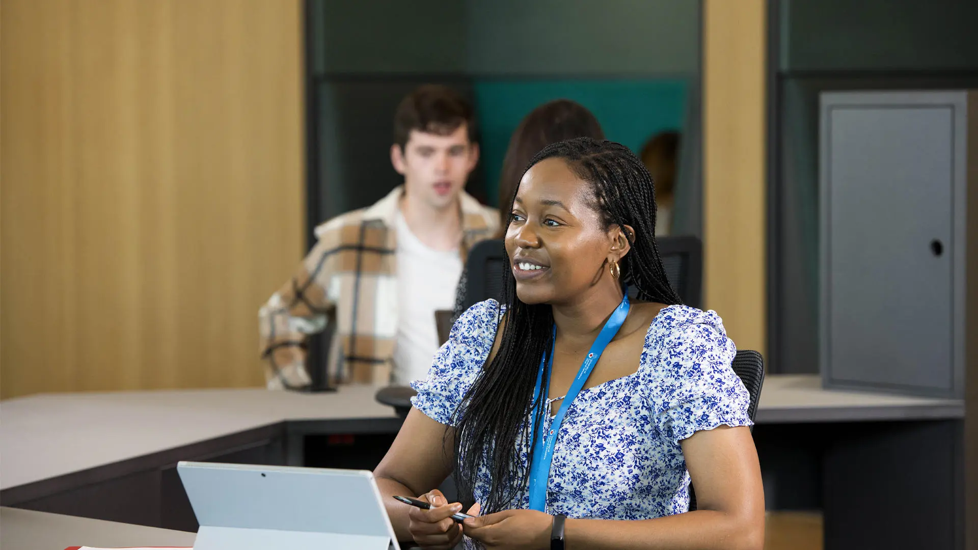 female student sat behind desk in the student centre smiling