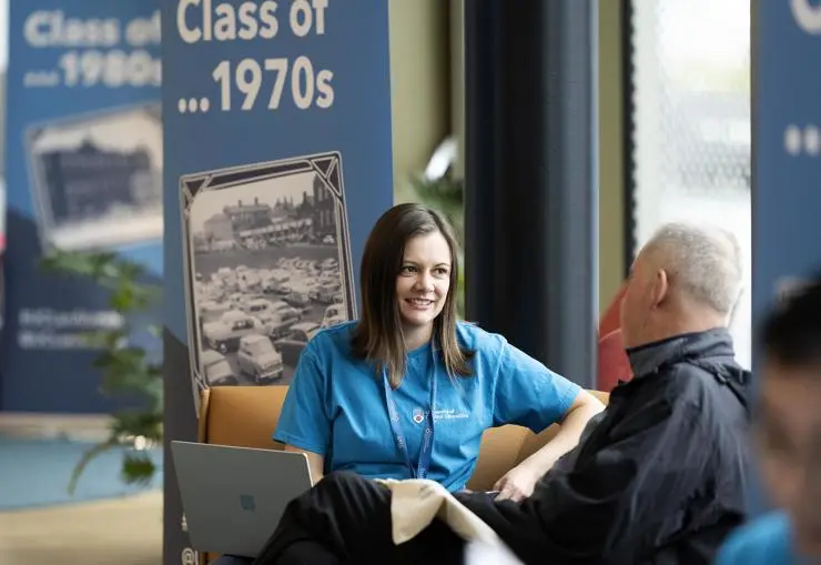 A visitor talking to a staff member at the 1970s stand
